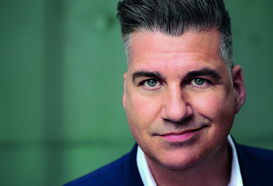 Porträt eines Mannes in blauem Anzug vor einem grünen Hintergrund