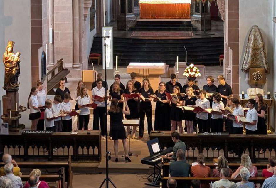 Das Bild zeigt viele Menschen in einer Kirche, vorne singt ein Chor