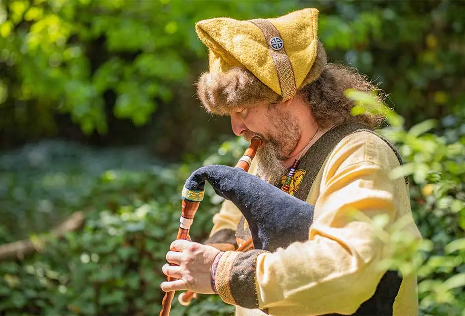 Ein Mann in mittelaterlicher Kleidung spielt auf einem Dudelsack